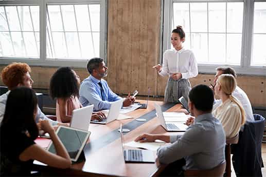 colleagues sit around a conference table with laptops listening to a tax presentation from a real estate professional